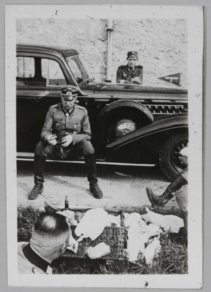 Le général Schaumburg, sur le marchepied de sa voiture, mangeant avec deux  officiers sous les yeux d'un soldat (de la 225. Infanterie-Division?) |  Paris Musées